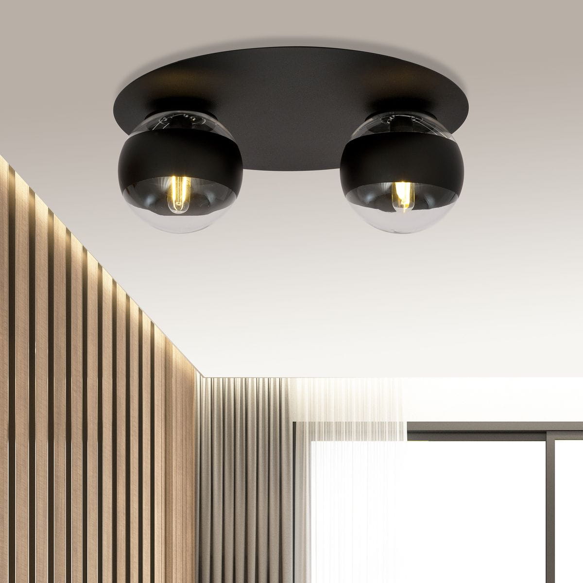 Czarna sufitowa lampa 2-punktowa z matowym metalowym stelażem i dwiema szklanymi kulami. Kule mają dekoracyjne żarówki LED, zawieszone na równym poziomie. Lampa zamontowana na jasnym tle z drewnianą i materiałową teksturą w otoczeniu.