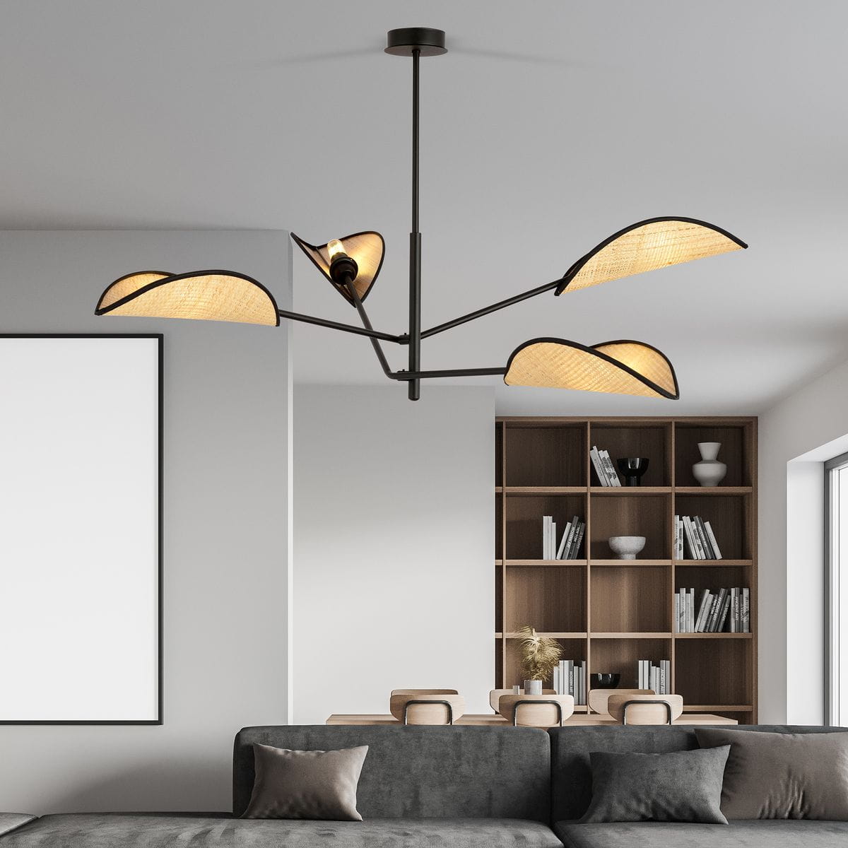 Czarna lampa sufitowa 4-punktowa Vene z rattanowymi kloszami w kształcie fal, zawieszona na cienkim stelażu. Ujęcie z góry, w tle widoczny regał z książkami oraz meble w neutralnych kolorach.