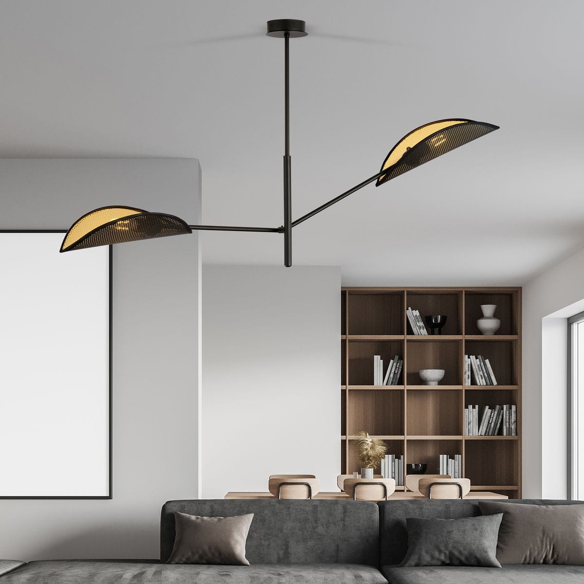 Lampa sufitowa Vene 2-punktowa w kolorze czarnym i złotym. Posiada dwa asymetryczne klosze w formie półksiężyca, zamocowane na cienkiej, metalowej konstrukcji. Ujęcie z dołu na tle minimalistycznego wnętrza z regałem.