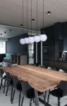 Lampa wisząca Camina 5-punktowa, czarna, z pięcioma kulistymi kloszami w białym kolorze, zawieszona nad drewnianym stołem w nowoczesnej kuchni. Klosze zawieszone na cienkich linkach, w minimalistycznym wnętrzu z ciemnymi ścianami.