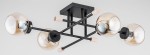 Czarna lampa sufitowa 4-punktowa z metalowymi ramionami w kształcie krzyża. Szklane klosze w odcieniu złota z widocznymi żarówkami. Elementy drewniane przy mocowaniach. Produkt zamontowany na prostokątnej podstawie.