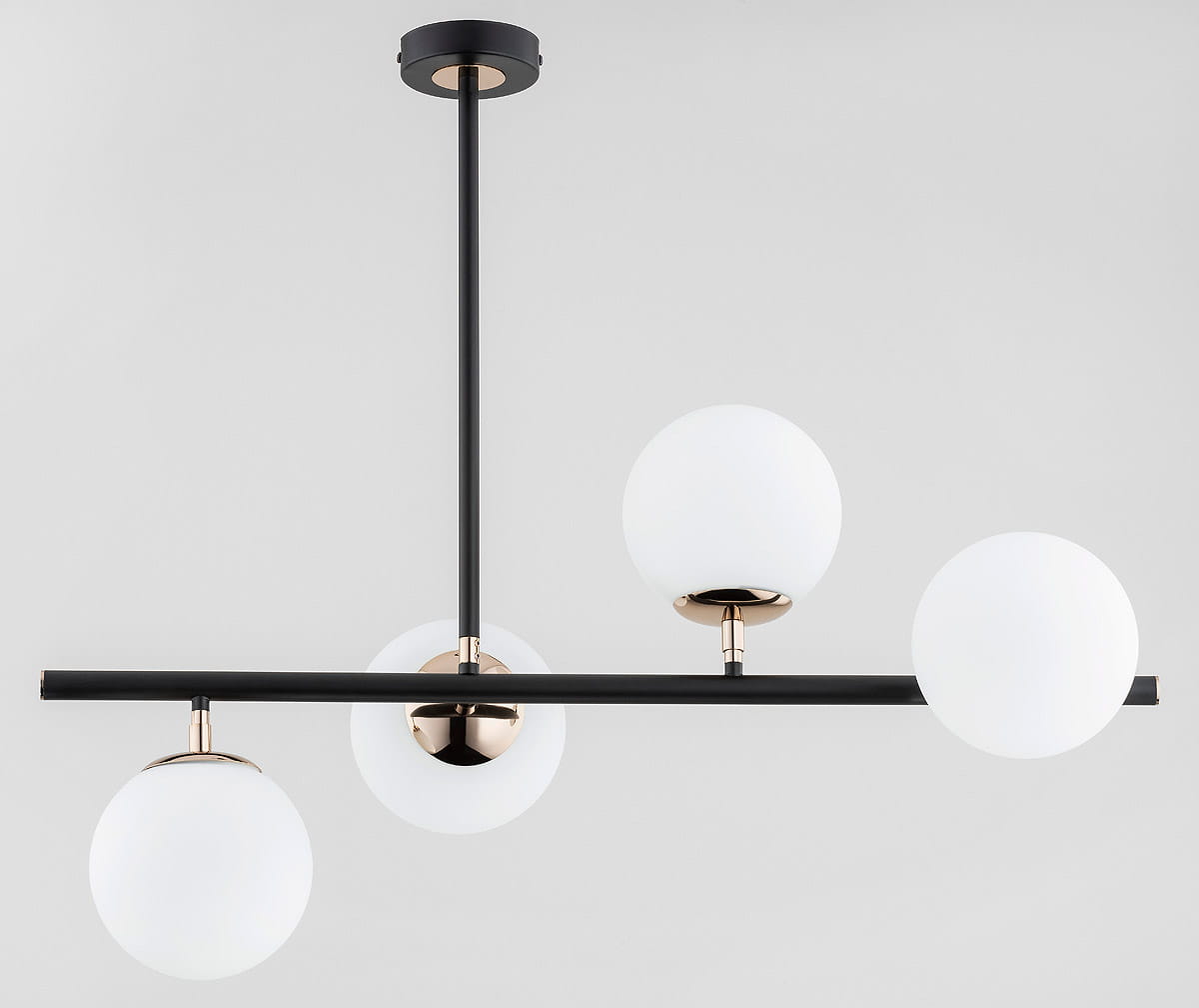 Lampa wisząca Luro White, 4-punktowa, z czarnym metalowym stelażem i złotymi detalami. Wyposażona w cztery okrągłe, matowe klosze w białym kolorze, zawieszona na długim, prostokątnym ramieniu. Ujęcie z góry, na jednolitym tle.