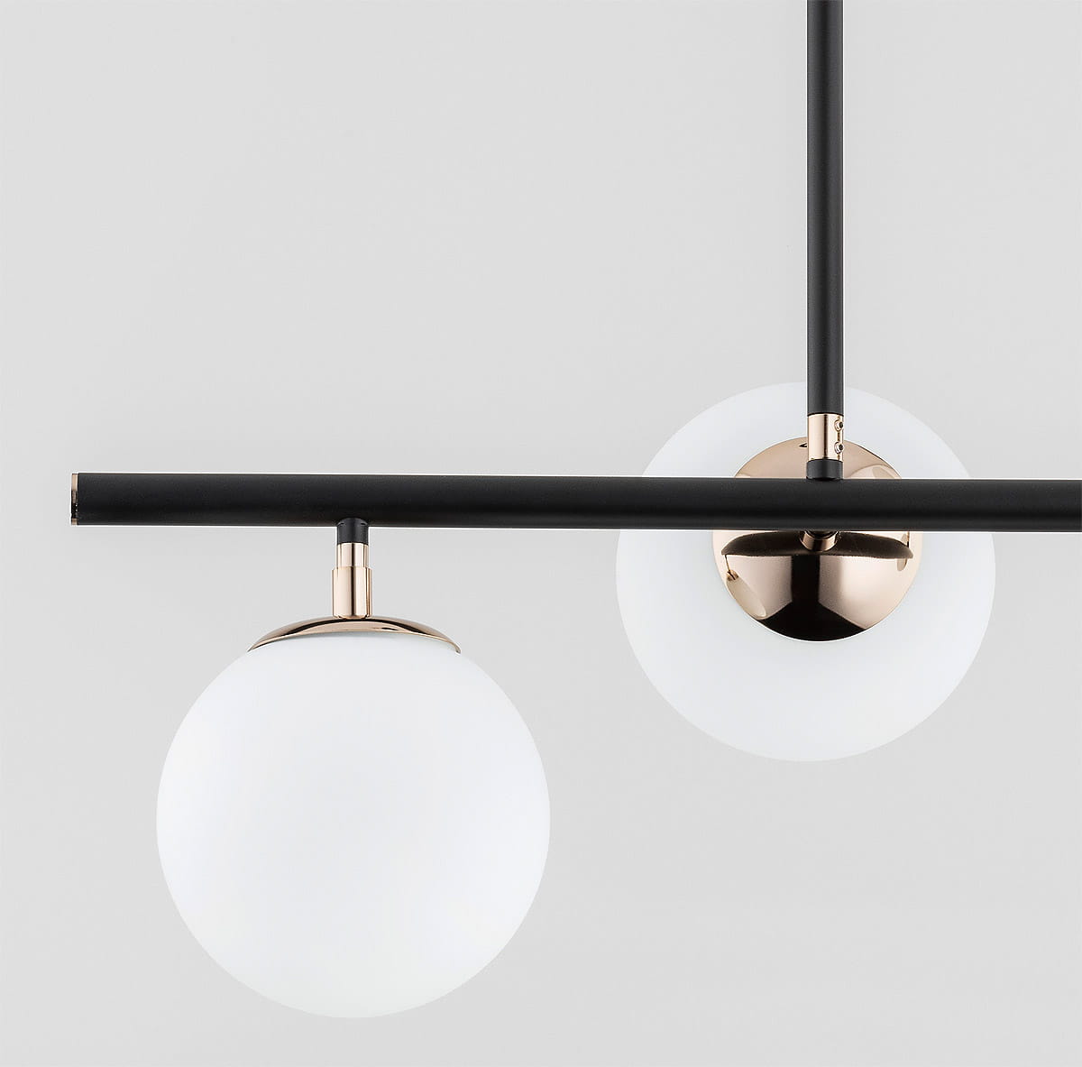 Luro White lampa wisząca 4-punktowa w kolorze czarnym i złotym. Składa się z czterech białych, okrągłych kloszy z matowego szkła, zawieszonych na czarnym metalowym stelażu z złotymi detalami. Ujęcie z przodu, na jednolitym szarym tle.