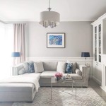 Lampa wisząca Abu Dhabi 5-punktowa w kolorze chromu z okrągłym abażurem, zawieszona w jasnym wnętrzu. Elementy chromowane oraz pięć źródeł światła. Otoczenie z szarymi ścianami, szarym narożnikiem i szklanym stolikiem.