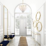 Lampa wisząca Tromso 5-punktowa w kolorze złotym, zawieszona w eleganckim wnętrzu. Posiada elementy z przezroczystego materiału i złote detale. W tle widoczna jasna przestrzeń z dużymi oknami i dekoracyjnymi lustrami.