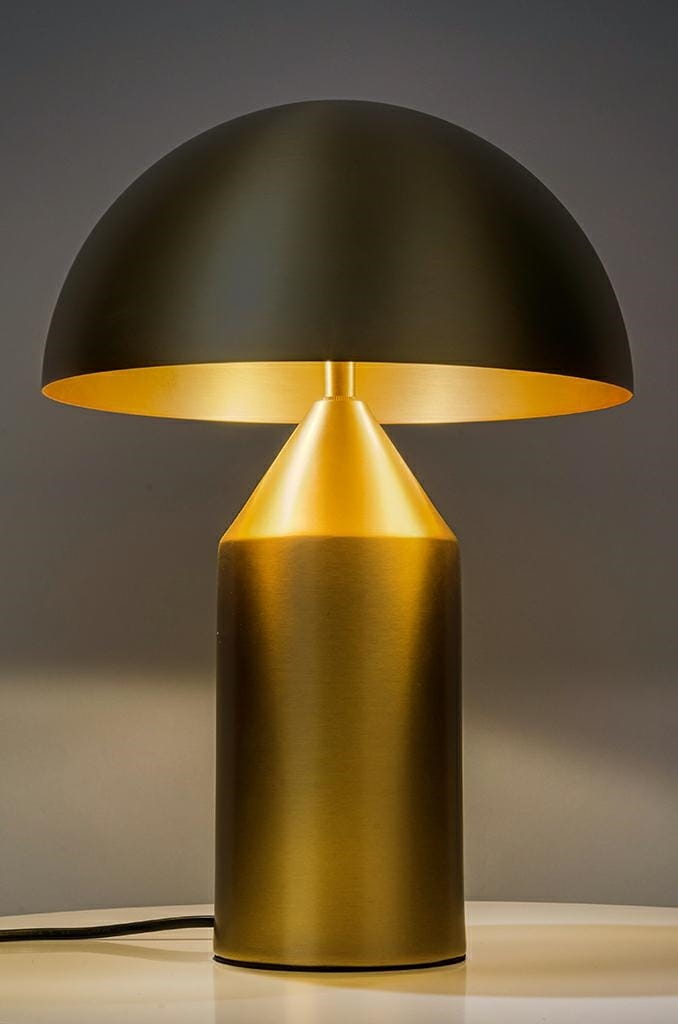 Lampa biurkowa Fungo w kolorze złotym z mosiądzu. Posiada cylindryczną podstawę i półokrągły klosz. Ujęcie frontalne, ukazujące elegancki design i matową fakturę. Kabel widoczny na dole.