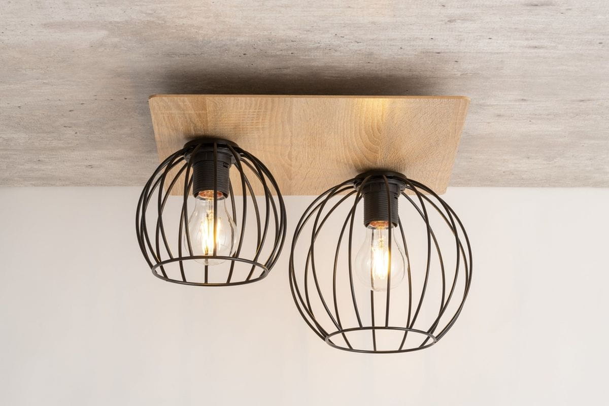 Czarna lampa sufitowa 2-punktowa z metalowymi kloszami w formie siatki, umocowana na prostokątnej podstawie w kolorze dąb. Ujęcie frontalne, lampa zamontowana na gładkim, jasnym tle. Widoczne żarówki w kloszach.