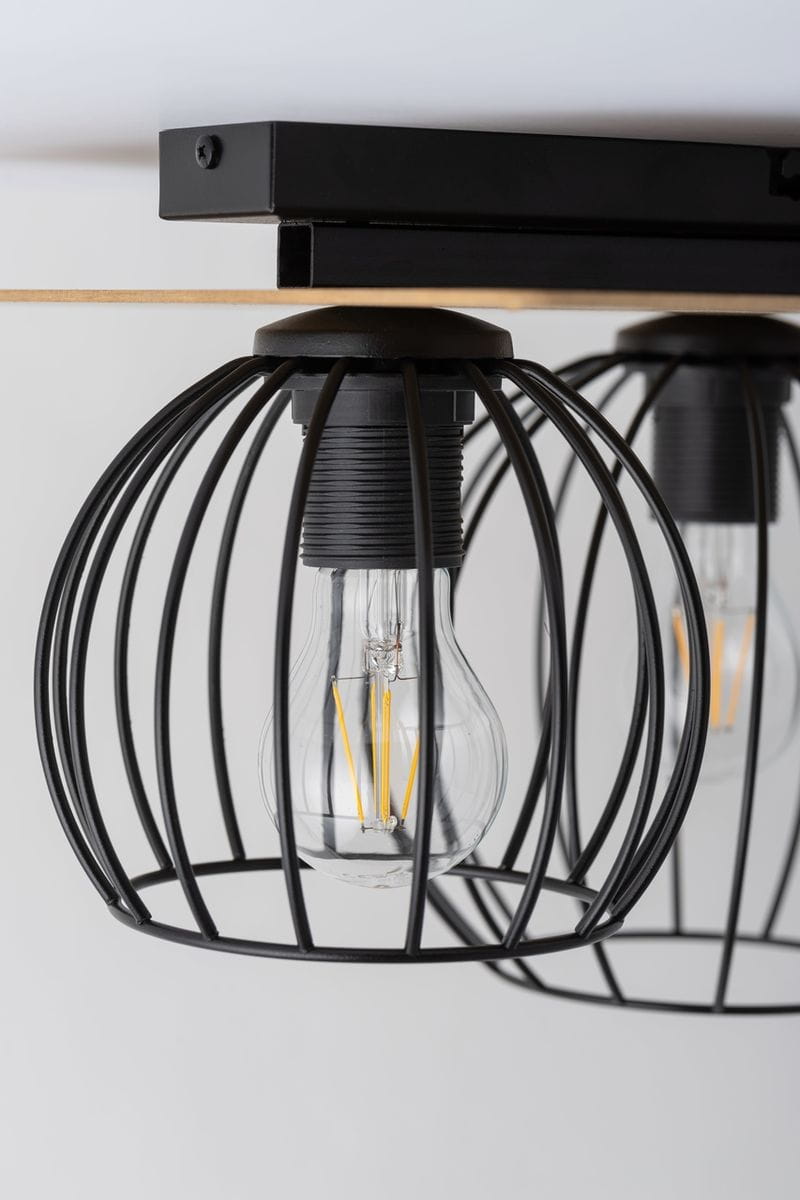 Czarna lampa sufitowa 2-punktowa z metalowymi kloszami w kształcie siatki, odsłaniającymi żarówki. Montaż pod sufitem, z drewnianym akcentem. Widok z dołu, ukazujący detale konstrukcji i źródła światła.