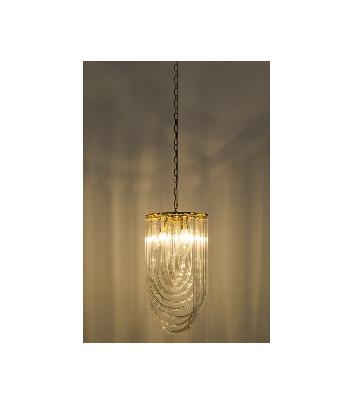 Lampa wisząca Murano L w kolorze złotym z trzema punktami świetlnymi. Posiada dekoracyjne, przezroczyste elementy w kształcie fal, zawieszona na złotej łańcuchu. Ujęcie z przodu, na prostym tle.