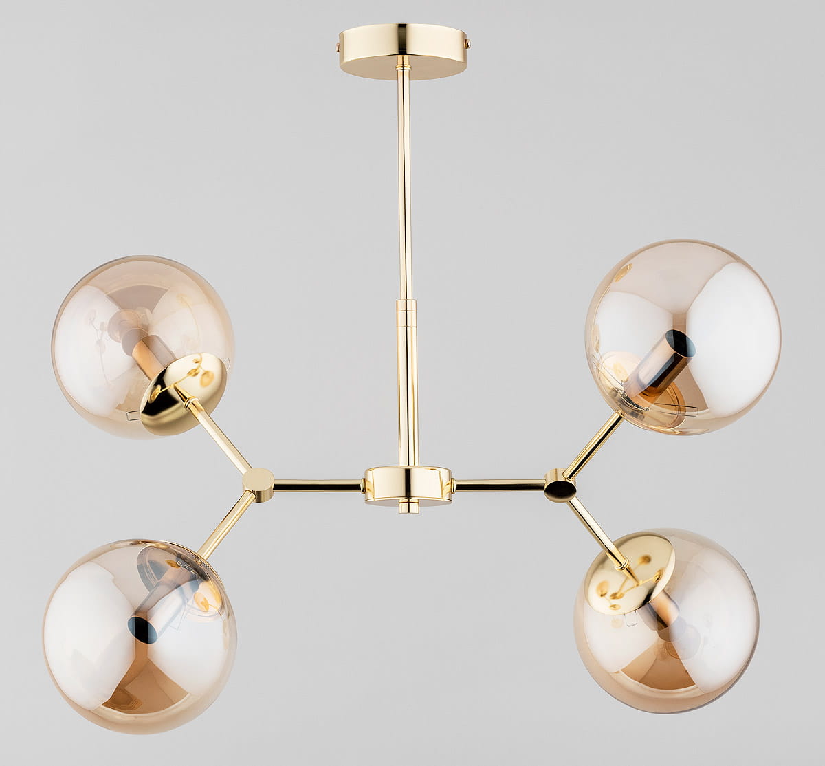 Lampa wisząca Foton Gold w kolorze złotym, z czterema szklanymi kloszami w odcieniu bursztynowym, zamontowana na prostym stelażu. Ujęcie frontalne pokazuje równomierne rozmieszczenie kloszy, które emitują światło w różnych kierunkach.