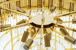 Lampa wisząca Imperial D80 z 16 punktami świetlnymi, w złotym kolorze. Kąt ujęcia z góry ukazuje centralną część z metalowymi ramionami oraz przezroczystymi kloszami, które emitują światło. Elegancki, nowoczesny design z wyraźnymi detalami.