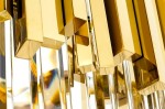 Złota lampa wisząca Imperial D60, 12-punktowa, z prostokątnymi elementami. Widoczne błyszczące detale i przezroczyste akcenty, ukazujące nowoczesny design. Ujęcie z bliska, koncentrujące się na strukturze i fakturze.