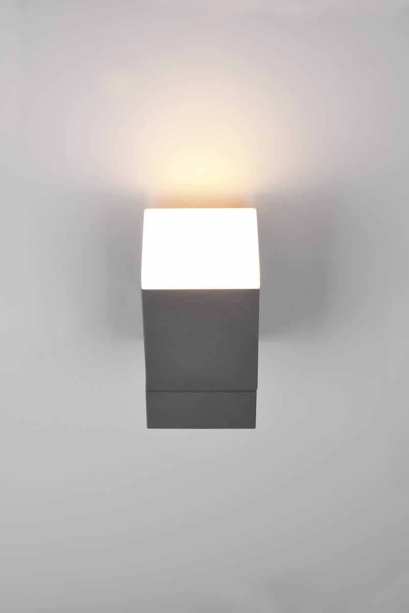 Avon LED kinkiet zewnętrzny w kolorze antracytowym, w formie prostokątnej, zamontowany na ścianie. Źródło światła emitujące ciepłe światło znajduje się na górze, tworząc efektowną iluminację. Prosty, nowoczesny design.