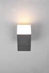 Avon LED kinkiet zewnętrzny w kolorze antracytowym, w formie prostokątnej, zamontowany na ścianie. Źródło światła emitujące ciepłe światło znajduje się na górze, tworząc efektowną iluminację. Prosty, nowoczesny design.