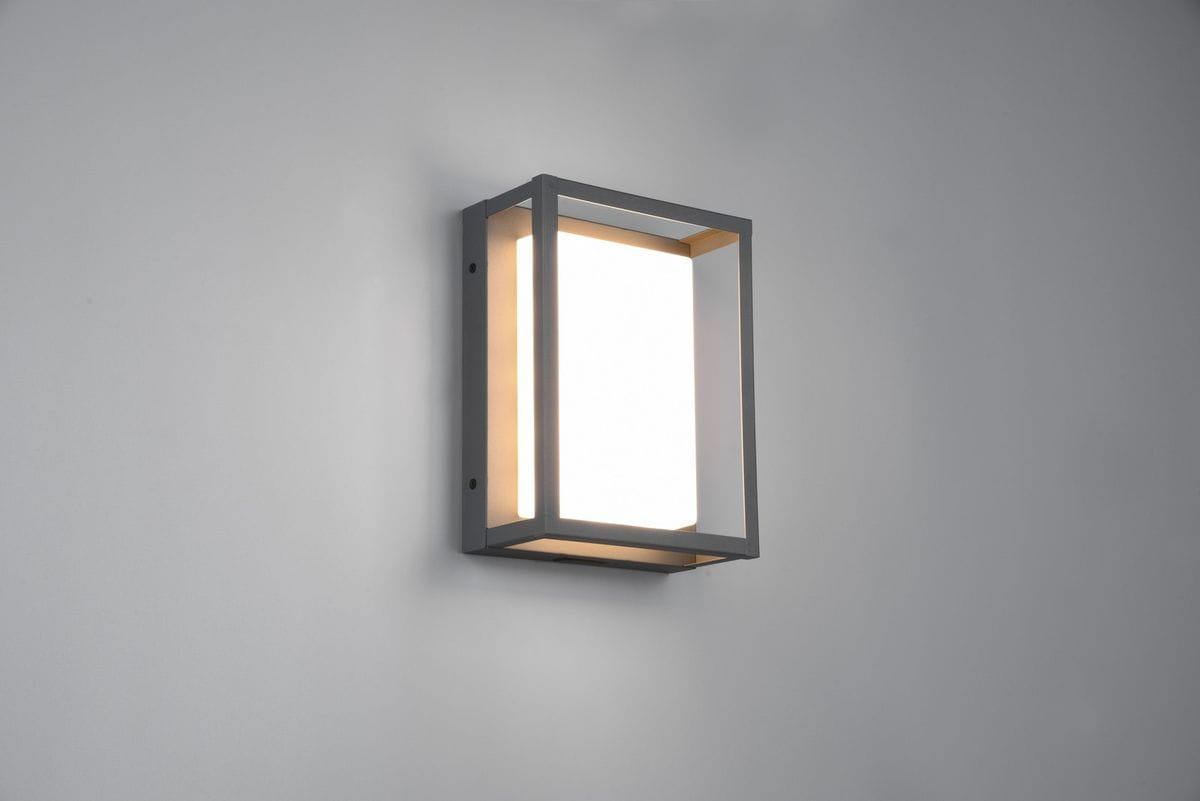 Kinkiet zewnętrzny Witham LED w antracytowej obudowie, prostokątny kształt z przezroczystym panelem świetlnym, zamontowany na ścianie, z widocznymi otworami do mocowania. Idealny do oświetlenia przestrzeni zewnętrznych.