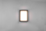 Kinkiet zewnętrzny Witham LED w kolorze antracytowym, o prostokątnym kształcie, zamontowany na ścianie. Emituje miękkie, ciepłe światło przez mleczną szybkę. Minimalistyczny design, idealny do nowoczesnych przestrzeni zewnętrznych.