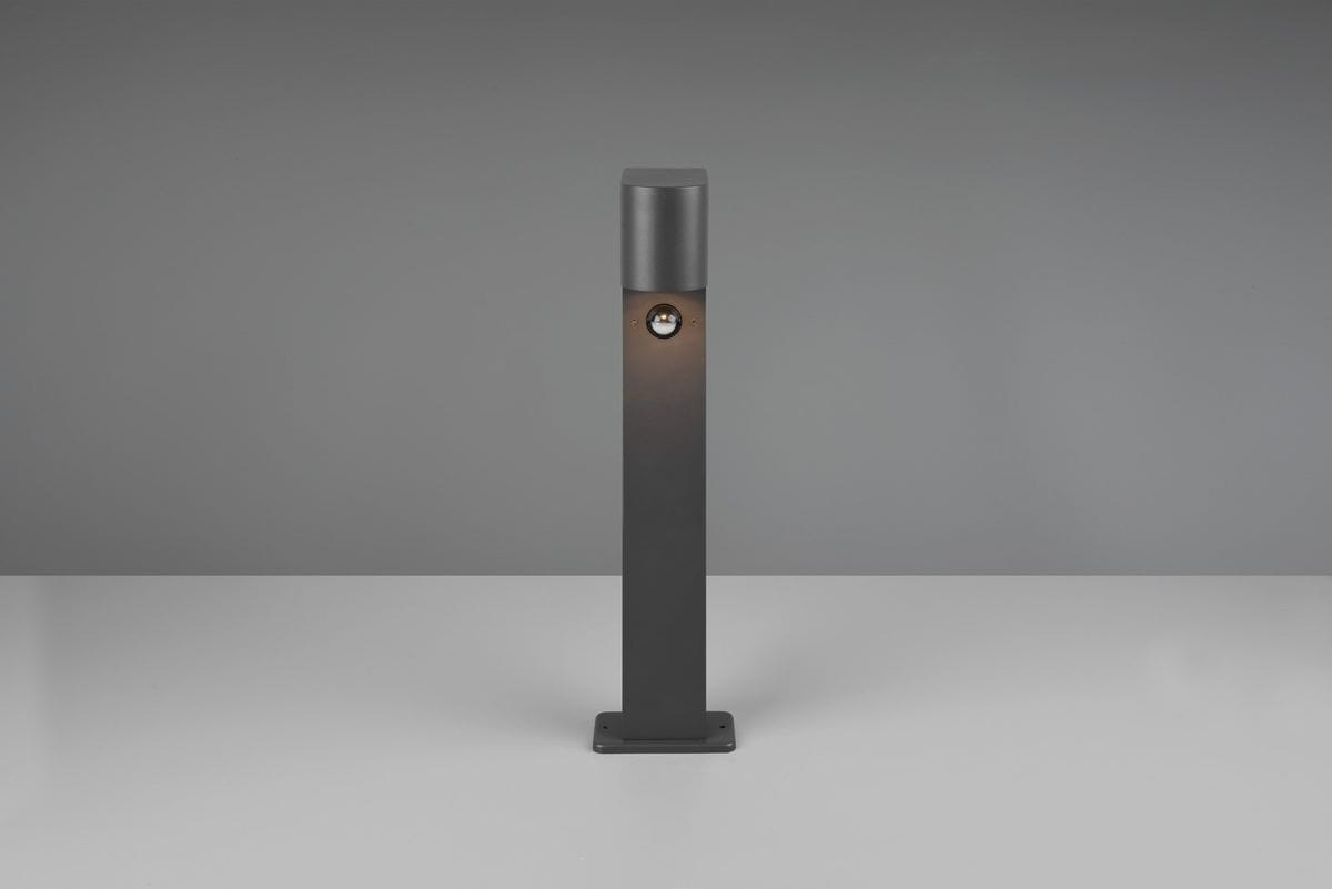 Lampa stojąca ogrodowa Roya H50 w kolorze antracytowym, z czujnikiem ruchu, o prostokątnym kształcie. Ujęcie frontalne, produkt stoi na płaskiej powierzchni. Źródło światła umieszczone w górnej części lampy. Tło jednolite, szare.