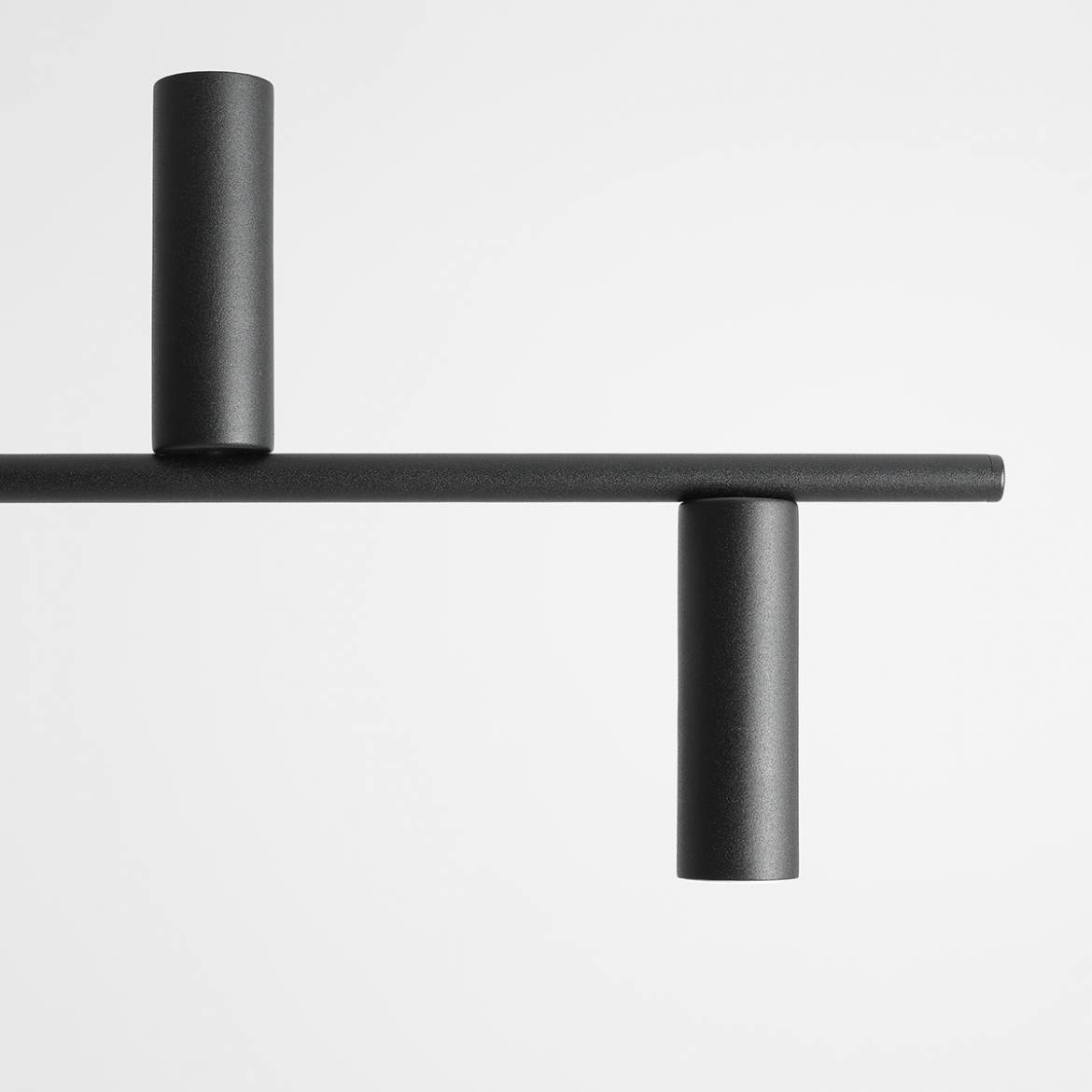Lampa wisząca Trevo 6-punktowa w kolorze czarnym. Konstrukcja z prostokątnym ramieniem i sześcioma cylindrycznymi uchwytami na źródła światła. Ujęcie z góry, na jednolitym tle. Matowe wykończenie, minimalistyczny design, idealna do nowoczesnych wnętrz.