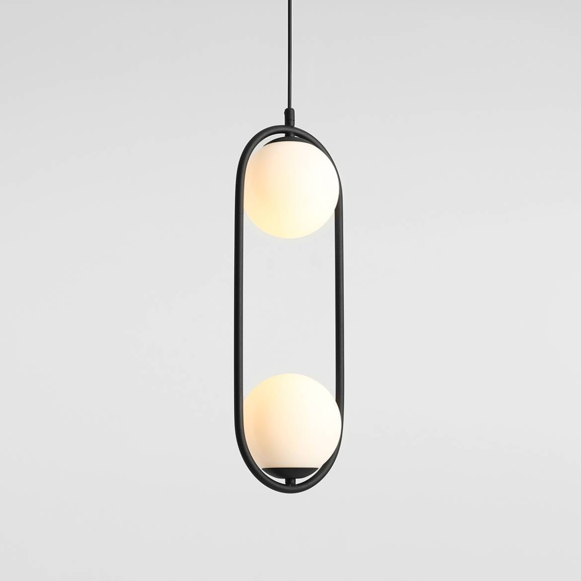 Lampa wisząca Riva 2-punktowa w kolorze czarnym, z dwoma okrągłymi kloszami w odcieniu białym, zawieszona na cienkim przewodzie. Kształt lampy jest prostokątny z zaokrąglonymi krawędziami, w minimalistycznym stylu. Tło jednolite, jasne.