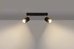 Czarna lampa sufitowa Nero z dwoma punktami świetlnymi. Oświetlenie w formie reflektorów z metalowymi złotymi detalami, zamontowane na prostokątnej podstawie. Ujęcie frontalne, lampa zwrócona w dół, emitująca ciepłe światło na ścianę.