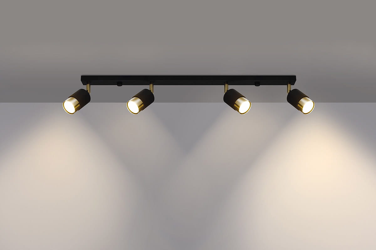 Czarna lampa sufitowa (spot) 4-punktowa z złotymi detalami, zamontowana na płaskiej podstawie. Reflektory są skierowane w dół, co podkreśla ich okrągły kształt i kontrastującą fakturę. Tło jest jednolite, co uwydatnia produkt.