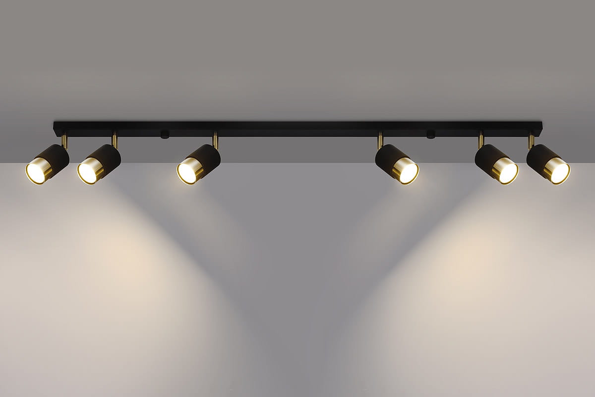 Czarna lampa sufitowa (spot) 6-punktowa z złotymi detalami. Ułożona poziomo, z pięcioma ruchomymi reflektorami, które emitują ciepłe światło, montowana na gładkim tle. Wysokiej jakości metalowa konstrukcja, minimalistyczny design.