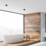 Czarna oprawa do zabudowy Nusa Round 1-punktowa, zamontowana w suficie, z minimalistycznym designem. Widoczna w nowoczesnej łazience z dużym oknem i drewnianymi panelami.