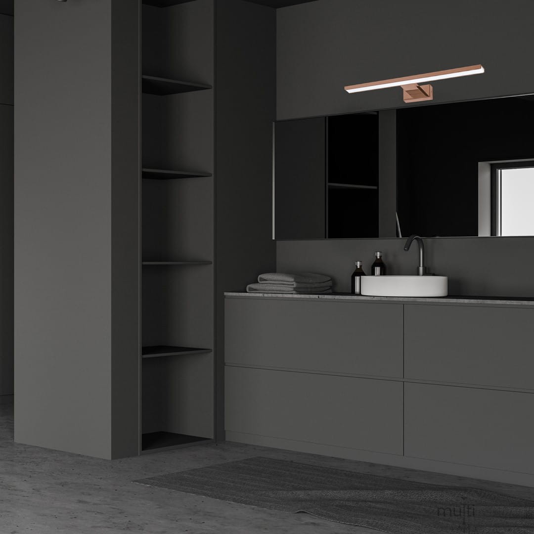 Kinkiet Shine LED IP44 w kolorze różowego złota, o długości 60 cm i mocy 13,8W, zamontowany nad umywalką w nowoczesnej łazience. Oświetlenie jest zamocowane na ciemnej ścianie, obok lusterka i zestawu kosmetyków.