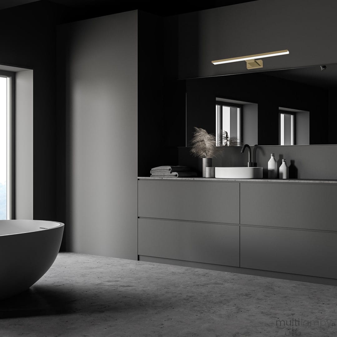 Kinkiet Shine LED IP44 w mosiężnym wykończeniu, umieszczony nad lustrem w nowoczesnej łazience. Lampa ma prostokątny kształt, emituje światło i jest zamontowana na ciemnym tle, w otoczeniu minimalistycznych akcesoriów łazienkowych.