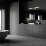 Kinkiet Shine LED IP44 w mosiężnym wykończeniu, umieszczony nad lustrem w nowoczesnej łazience. Lampa ma prostokątny kształt, emituje światło i jest zamontowana na ciemnym tle, w otoczeniu minimalistycznych akcesoriów łazienkowych.