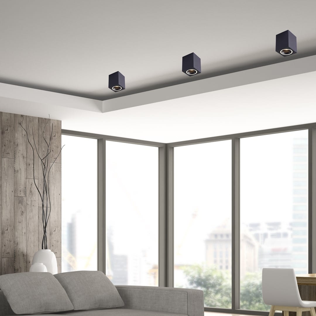 Czarna lampa sufitowa Bima Ring Square 1-punktowa, w kształcie prostokąta, zamontowana na suficie. Widoczna w nowoczesnym wnętrzu z dużymi oknami i minimalistycznym umeblowaniem.