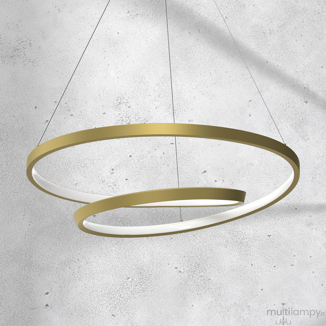 Lampa wisząca Lucero LED 1-punktowa w kolorze złotym, składająca się z dwóch okrągłych elementów, jeden większy i jeden mniejszy, z białym wnętrzem. Zawieszona na cienkich żyłkach, prezentująca nowoczesny design. Tło jest jasne, betonowe.