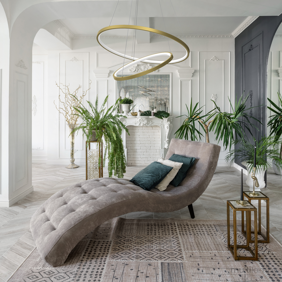 Złota lampa wisząca Lucero LED 1-punktowa, z dwoma okręgami, zawieszona we wnętrzu. Lampa znajduje się nad eleganckim fotelem w kształcie fali, otoczona roślinami oraz dekoracyjnymi elementami. Tło w jasnych kolorach, z detalami architektonicznymi.