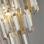 Lampa sufitowa Clarissa 5-punktowa w kolorze chromu, z transparentnymi, szklanymi elementami w kształcie prostokątów i trójkątów, które odbijają światło, tworząc efektowne refleksy. Widok z bliska na detale kryształów.