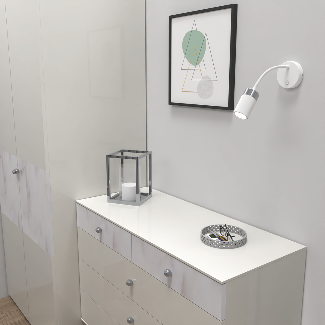 Kinkiet Joker Flex 1-punktowy w kolorze białym, z elastycznym ramieniem, zamontowany na ścianie obok minimalistycznego obrazu. W tle widoczna komoda z lustrzanym blatem, szklana latarnia i okrągła miska z akcesoriami.