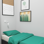 Biały kinkiet Joker Flex 1-punktowy, zamontowany na ścianie obok łóżka, z elastycznym ramieniem i cylindryczną oprawą. W tle widoczne obrazy w ramkach oraz pościel w odcieniach zieleni. Tło jednolite, jasne.