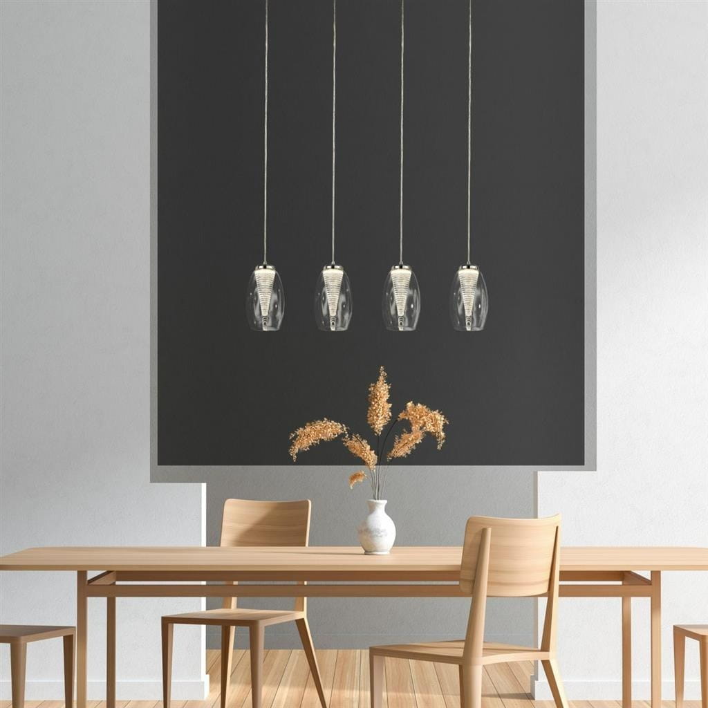 Lampa wisząca Cyclone LED 4-punktowa w chromowanej obudowie, z przezroczystymi kloszami, zawieszona na cienkich linkach. Produkt umieszczony nad drewnianym stołem w minimalistycznym wnętrzu z szarym tłem i wazonem z roślinami.
