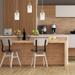 Lampa wisząca Madera 1-punktowa w białym kolorze z przezroczystym kloszem i drewnianym detalem, zawieszona w nowoczesnej kuchni. Widok frontalny, w tle drewniana zabudowa, stół z owocami i krzesła.