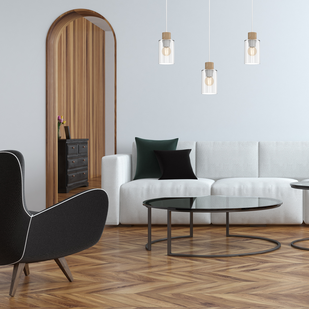 Lampa wisząca Madera 3-punktowa w białych szklanych kloszach z drewnianymi detalami. Zawieszona w nowoczesnym wnętrzu, nad białą sofą i okrągłym stolikiem, w jasnym pomieszczeniu z drewnianymi akcentami.