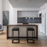 Lampa wisząca Duo 2, 3-punktowa, w kolorze chromu z przydymionymi kloszami. Zawieszona nad wyspą kuchenną, w nowoczesnym wnętrzu z białymi szafkami i drewnianym blatem. Widoczne czarne stołki barowe.