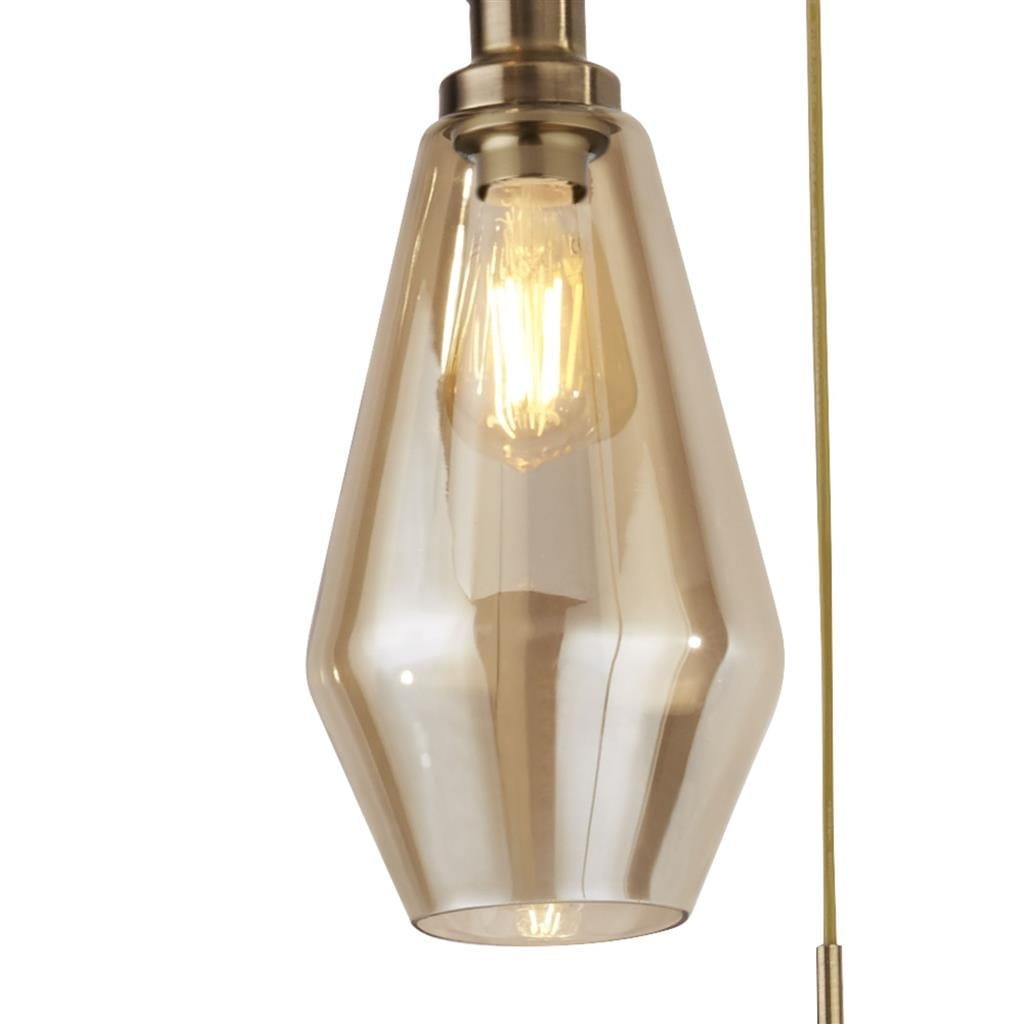 Lampa wisząca Mia 3-punktowa w antycznym mosiądzu. Zawieszona na cienkim kablu, z kloszem w kształcie kropli, wykonanym z przezroczystego szkła w ciepłym odcieniu. Widoczne żarówki w stylu retro wewnątrz kloszy.
