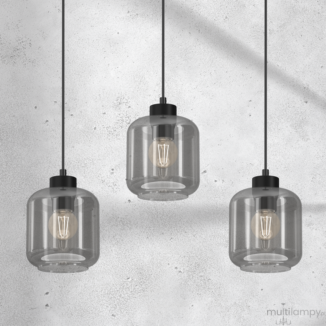 Lampa wisząca Sombra 3-punktowa, czarna z dymionymi kloszami. Klosze mają okrągły kształt, przymocowane do czarnych kabli. Widoczne żarówki o klasycznym kształcie, zawieszone w równych odstępach. Tło w odcieniach szarości.