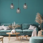 Lampa wisząca 3-punktowa Sombra w kolorze czarnym z dymionymi kloszami, zawieszona nad sofą w turkusowym kolorze. Klosze mają okrągły kształt, a w ich wnętrzu widoczne są żarówki. Tło w odcieniu zielonym, z dodatkami roślinnymi.