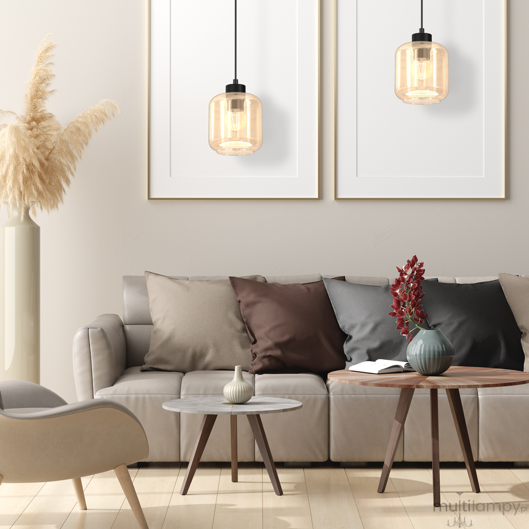 Lampa wisząca Sombra 1-punktowa w kolorze czarnym z bursztynowym kloszem, zawieszona nad sofą w nowoczesnym wnętrzu. Produkt ma prosty, cylindryczny kształt i jest umieszczony w centralnej części aranżacji.