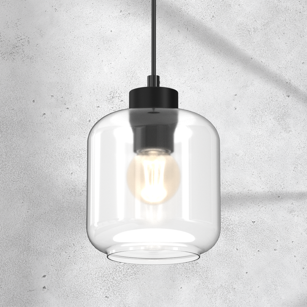 Lampa wisząca Sombra 1-punktowa, czarna z przezroczystym kloszem, o cylindrycznym kształcie. Widoczna żarówka w środku, zawieszona na cienkim przewodzie. Tło w kolorze szarym, betonowym, podkreślające minimalistyczny styl.