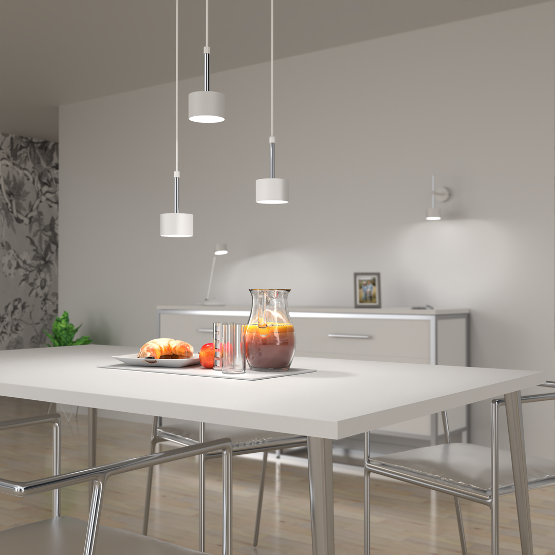 Lampa wisząca Arena 3-punktowa w kolorze białym i srebrnym, z trzema okrągłymi kloszami, zawieszona nad białym stołem w nowoczesnym wnętrzu. W tle widoczna szafka i dekoracyjne elementy.