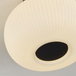 Czarna lampa sufitowa Lumina 10271-1BK o okrągłym, teksturowanym kloszu w białym kolorze z centralnym otworem, podświetlonym delikatnym światłem. Widok z góry, ukazujący detale wzoru oraz kontrast między bielą a czernią.