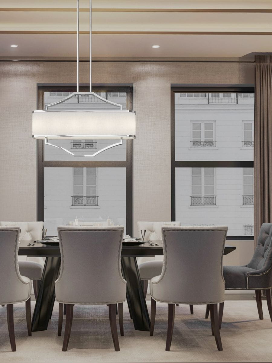 Lampa wisząca Gerdo Ovale Cromo 4-punktowa w chromowanej oprawie, o prostokątnym kształcie, zawieszona na dwóch cienkich linkach. W tle elegancka jadalnia z szarymi krzesłami i dużymi oknami, na jasnym tle.
