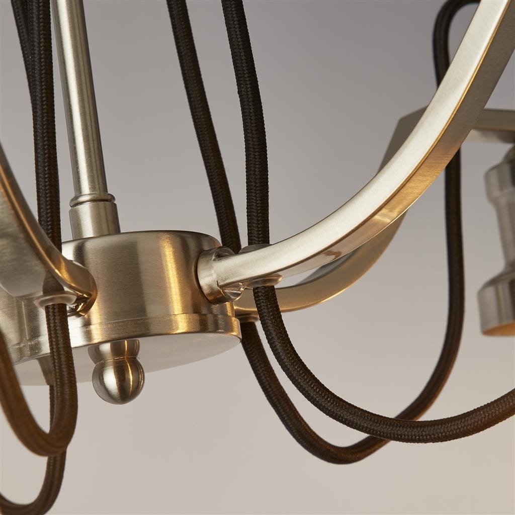 Lampa wisząca Olivia 5-punktowa w satynowym srebrze. Zbliżenie na metalową podstawę z czarnymi przewodami, gładkie łuki ramion oraz detal kulistego mocowania. Wykończenie matowe, elegancki wygląd.