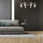 Lampa wisząca Olivia 8-punktowa w kolorze satynowego srebra, z widocznymi żarówkami, zawieszona nad szarym narożnikiem. Tło w ciemnym odcieniu, stół obok z rośliną i filiżanką, dywan w paski na podłodze.